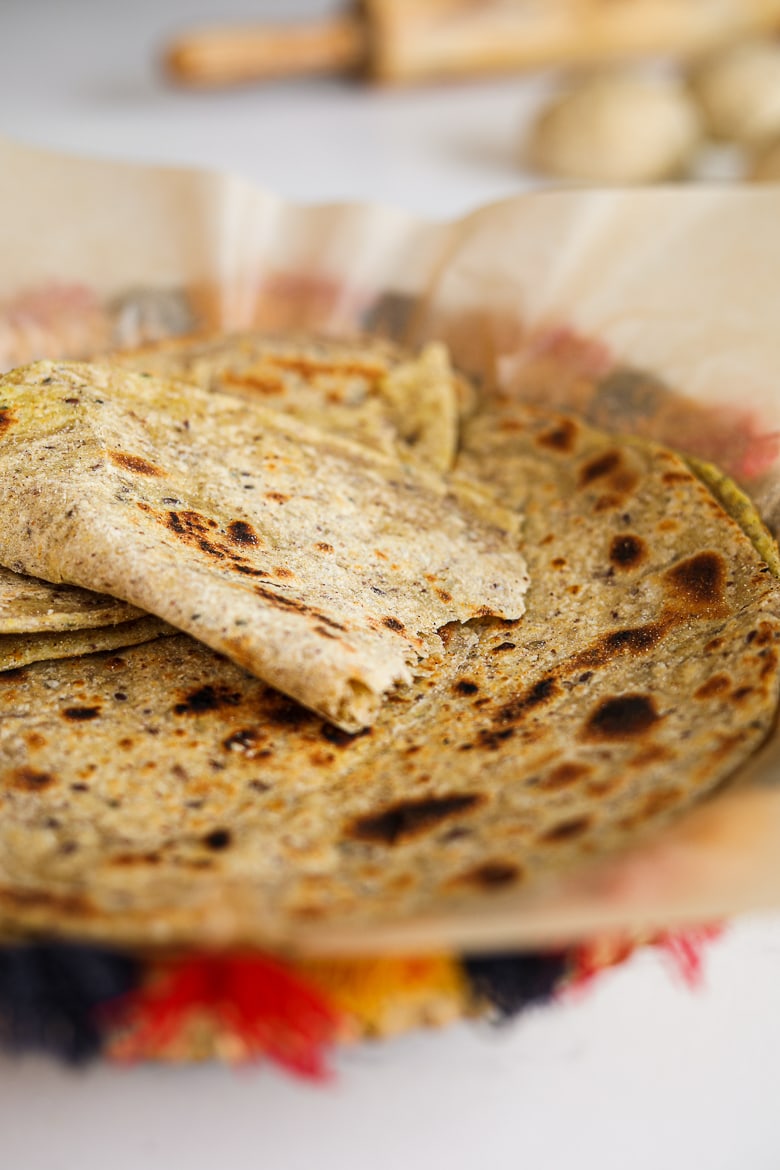 Close-up view of homemade paratha in a colourful traditional woven basket.