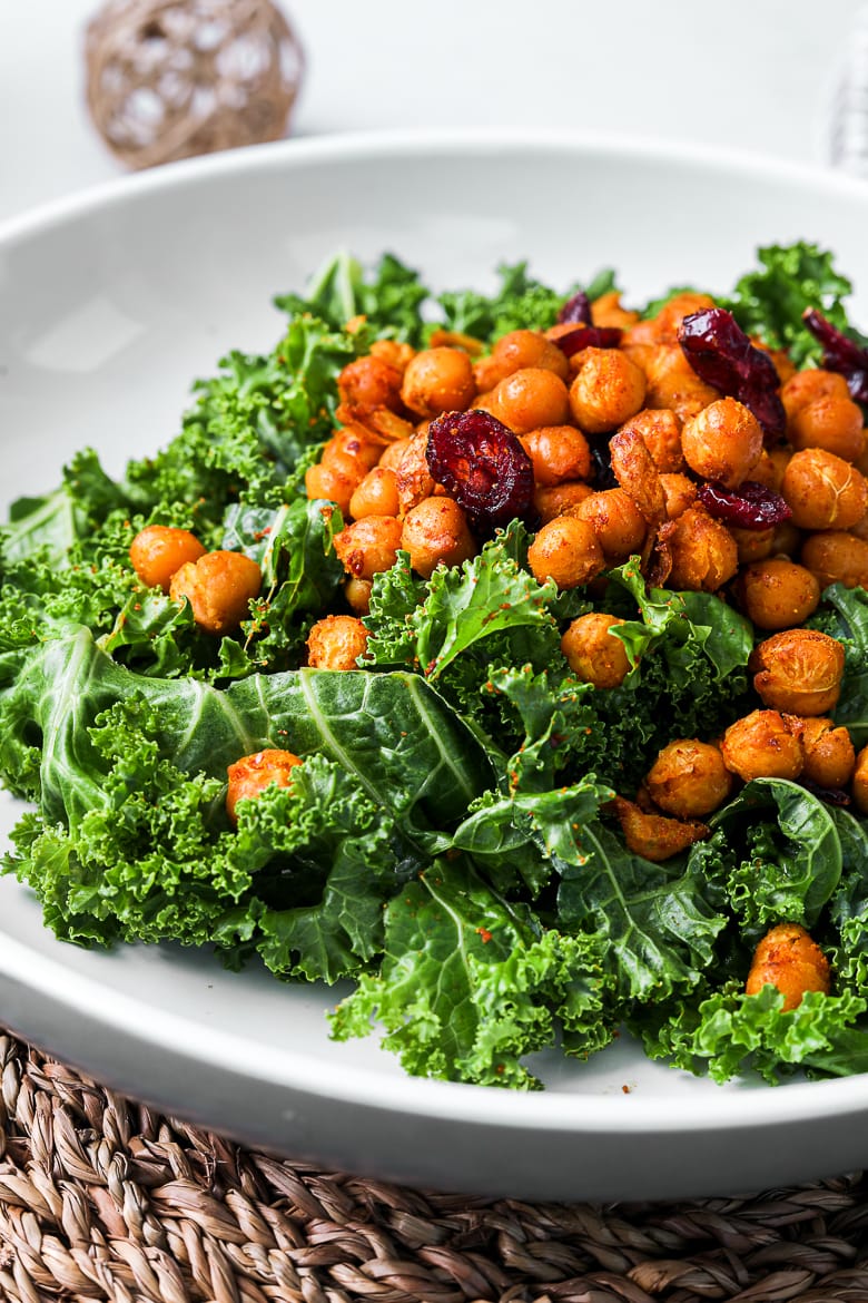 bowl of kale salad with spicy roasted chickpeas topped with cranberries