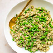 white bowl of farro and peas with gold spoon