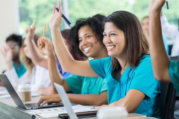 medical or nursing school students raise their hands to ask or answer a question during class