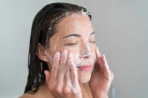 woman cleansing her face to prevent aduclt acne