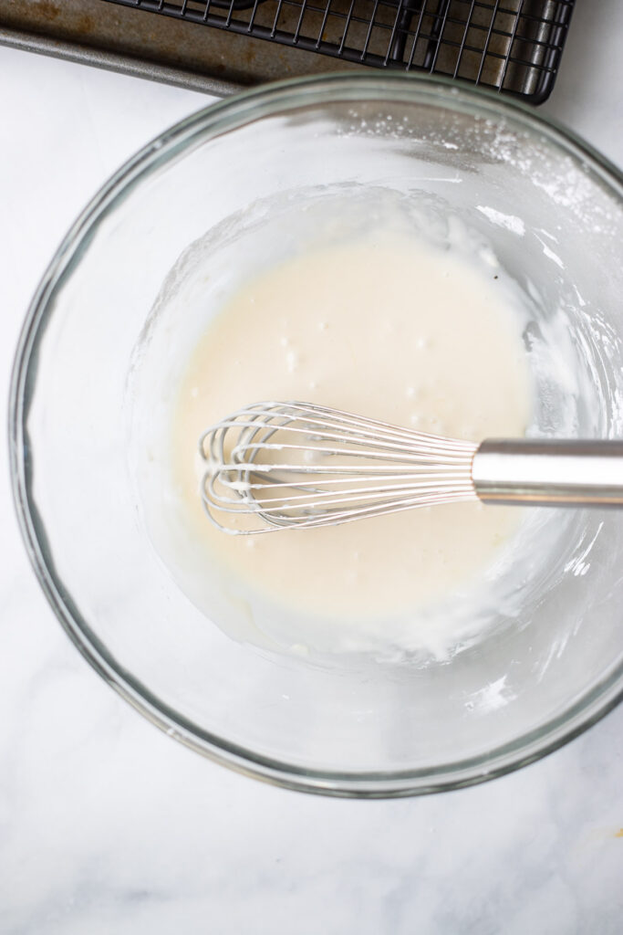 Add maple syrup and gradually add milk whisking until thick glaze forms.
