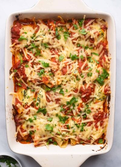 baked stuffed shells in baking dish garnished with fresh parsley.