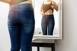 high cortisol levels can lead to weight gain woman looking at body in mirror