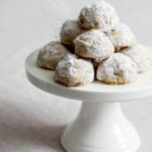 vegan pecan snowball cookies on a white cake stand