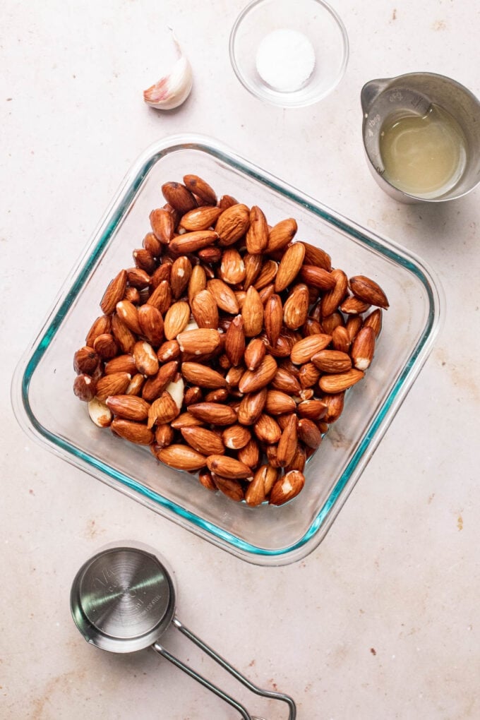 raw almonds in glass dish with measuring cups