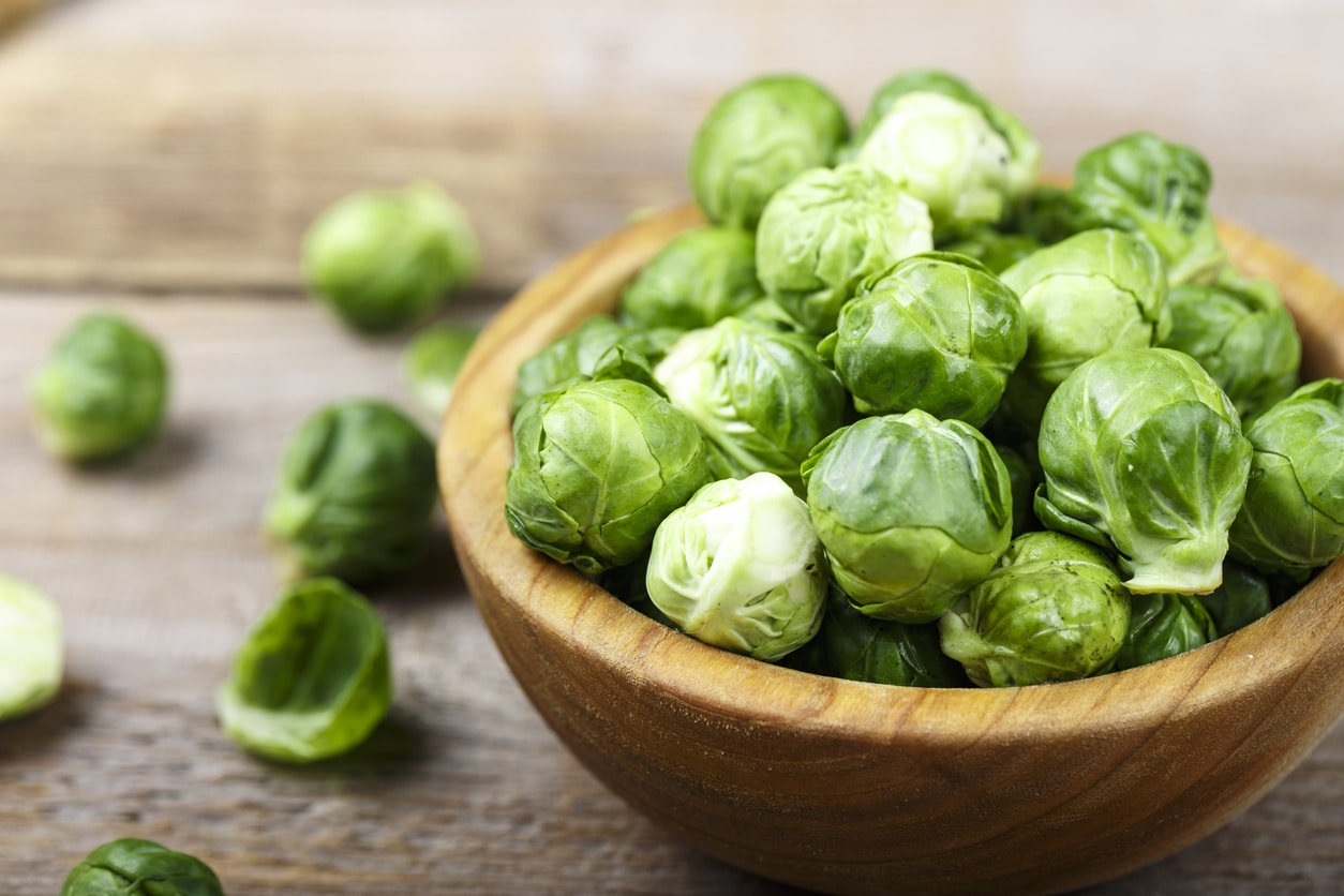fresh organic brussels sprouts raw in a plate on wooden background. space for text