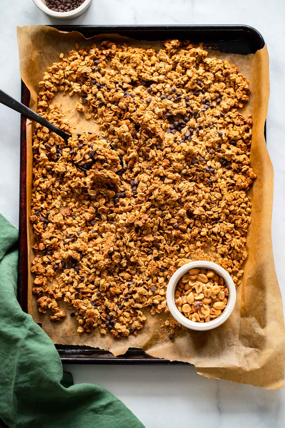 baked peanut butter granola with mini chocolate chips on a sheet pan lined with parchment paper. 