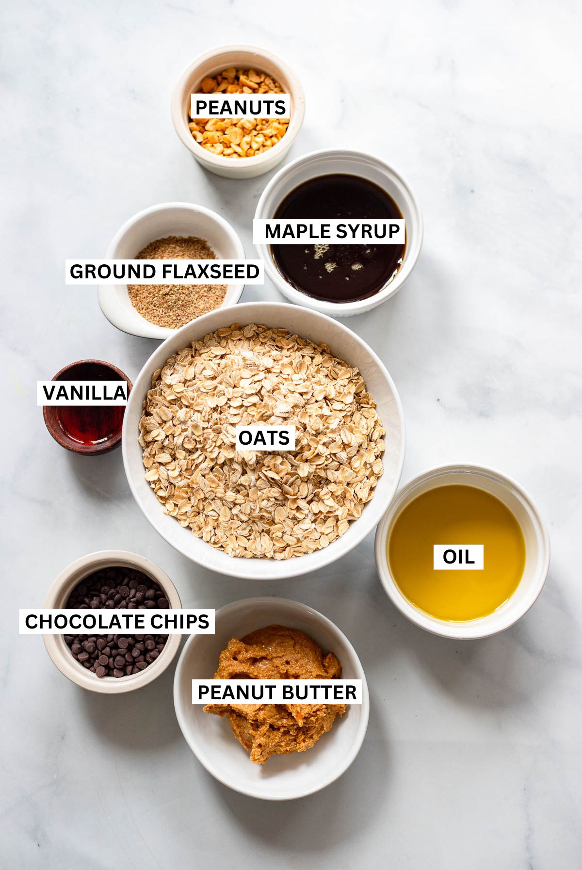 peanut butter granola ingredients in small bowls with text overlay labels.