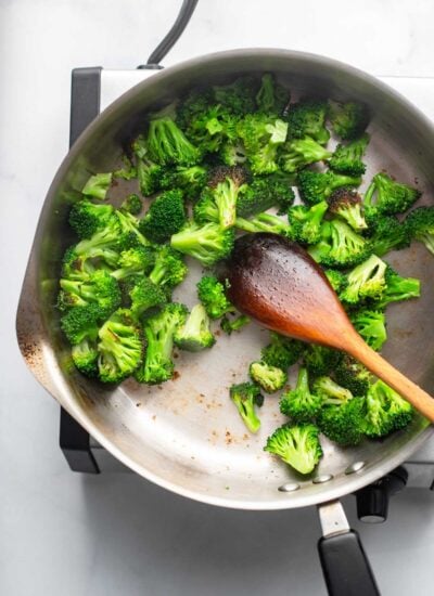 sautéed chopped broccoli in a skillet with a wooden spoon. 