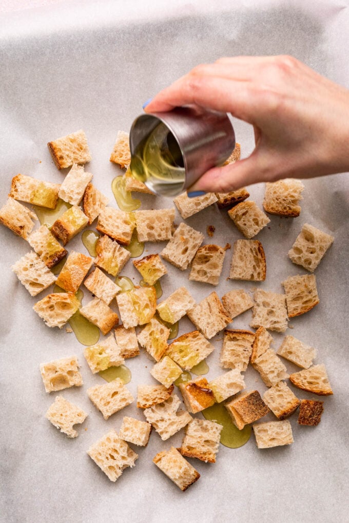 hand pouring oil on homemade croutons