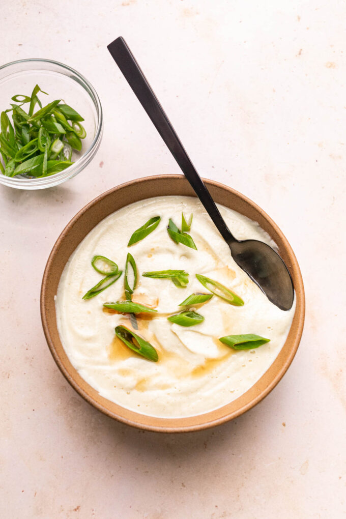 creamy vegan parsnip soup in brown bowl with green onions
