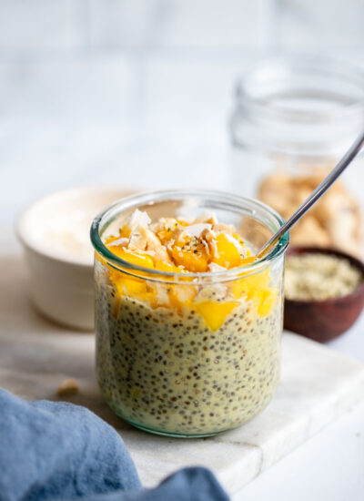 mango chia seed pudding in a glass topped with chopped mango and coconut.