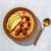 millet porridge in brown bowl with sugar and sliced pear