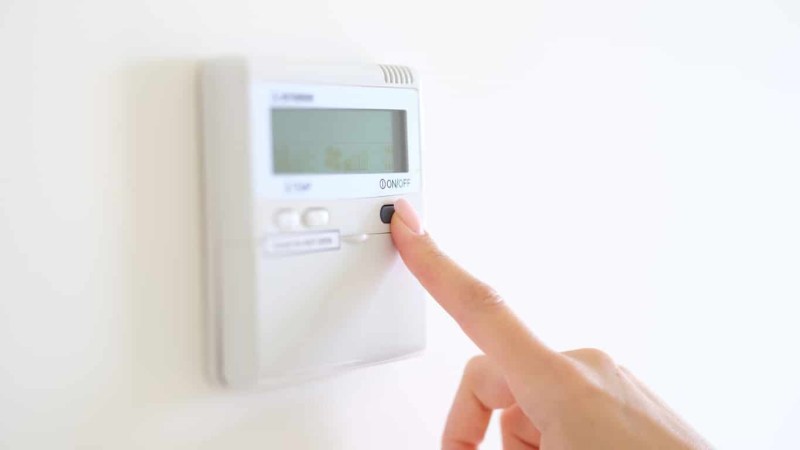 Woman changing the thermostat; thermometer; comfortable environment