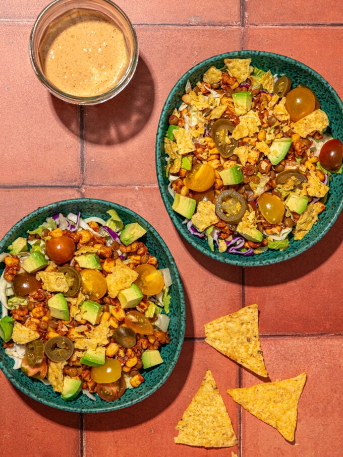 vegan taco salad in bowls with creamy dressing and chips